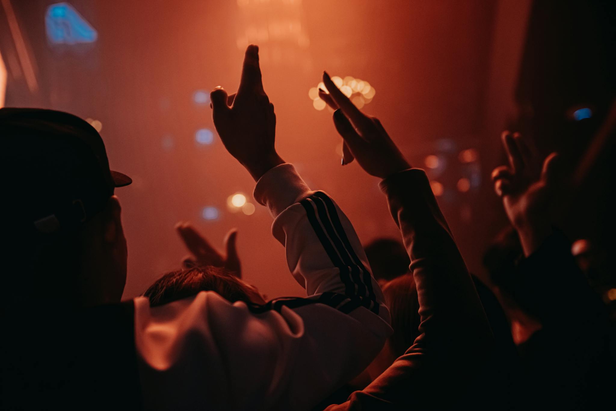 An energetic crowd enjoying a music concert with vibrant lighting and raised hands.